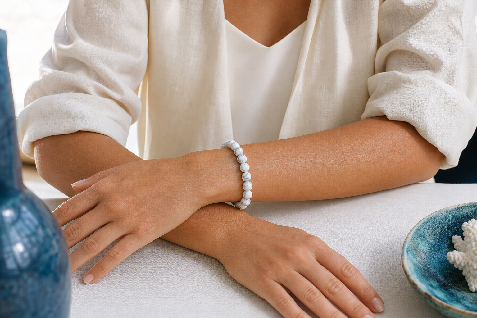 Bracelet en howlite porté au poignet gauche, les deux poignets visibles