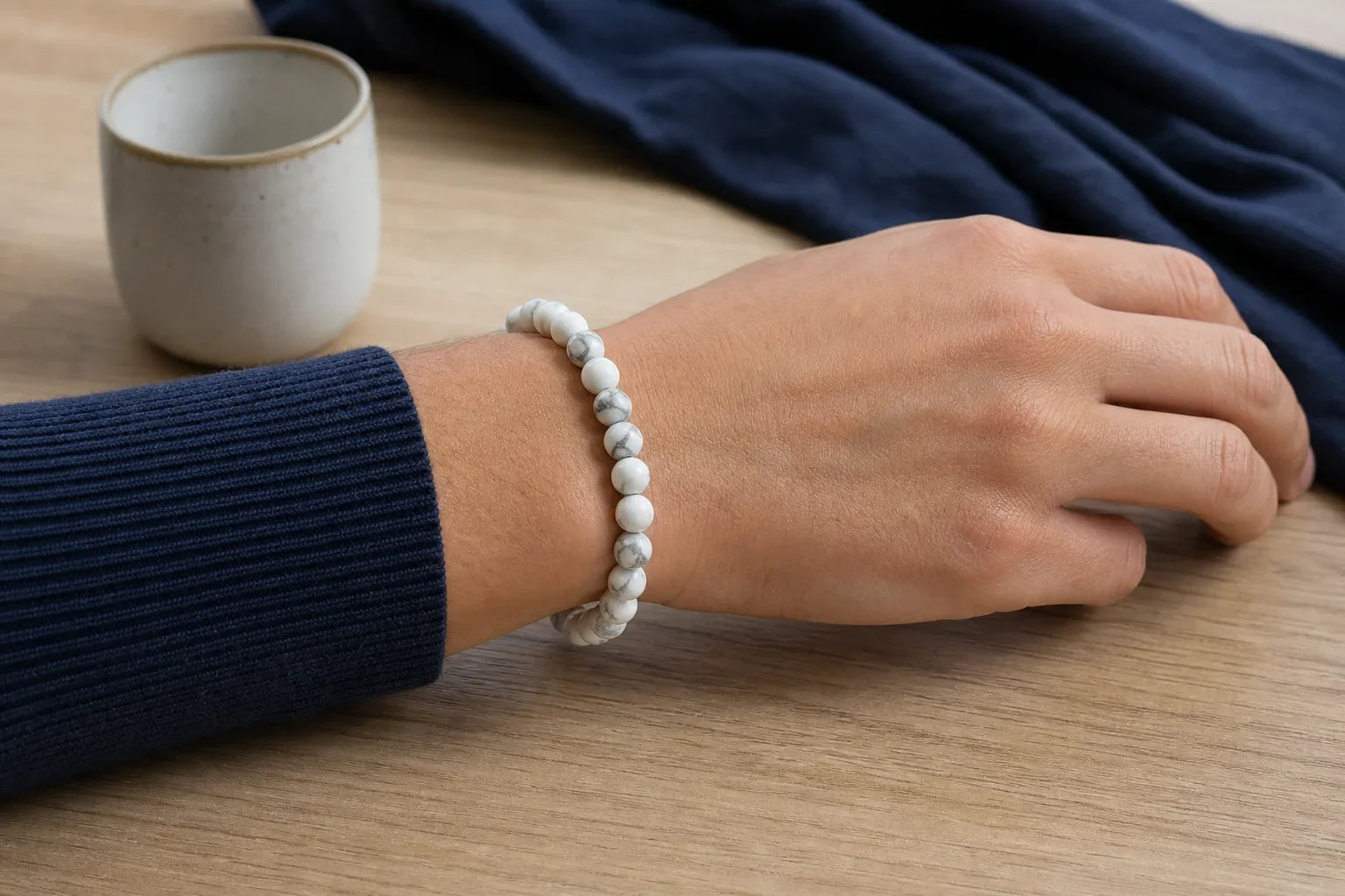 Bracelet en howlite blanche porté au poignet sur une table en bois clair