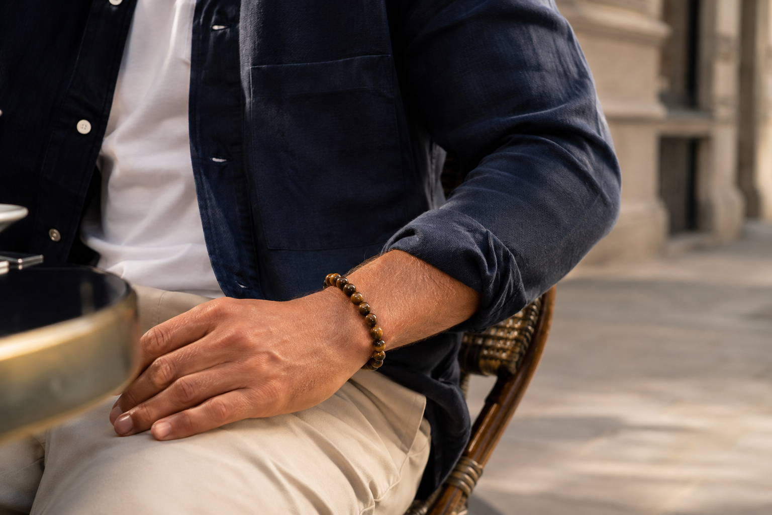 Homme portant un bracelet en œil de tigre avec une tenue bleu marine et beige