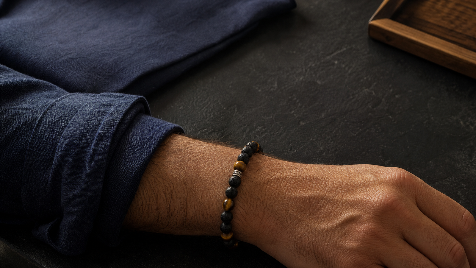 Bracelet associant pierre de lave noire et œil-de-tigre doré porté au poignet