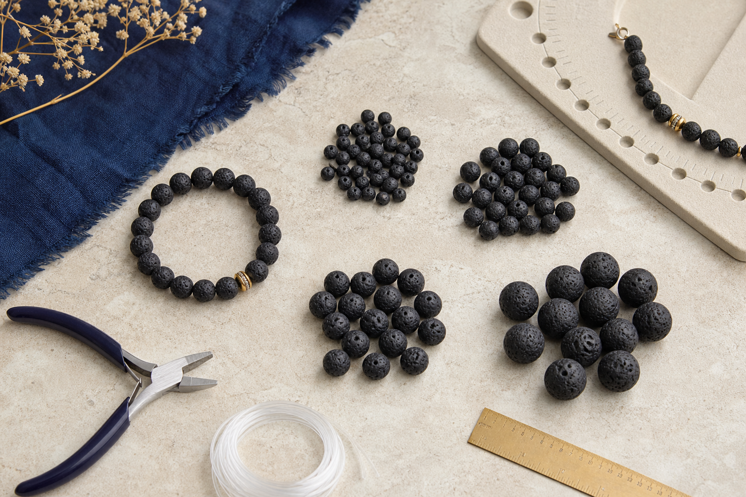 Perles de lave de plusieurs diamètres et bracelet élastique sur un établi de bijoutier