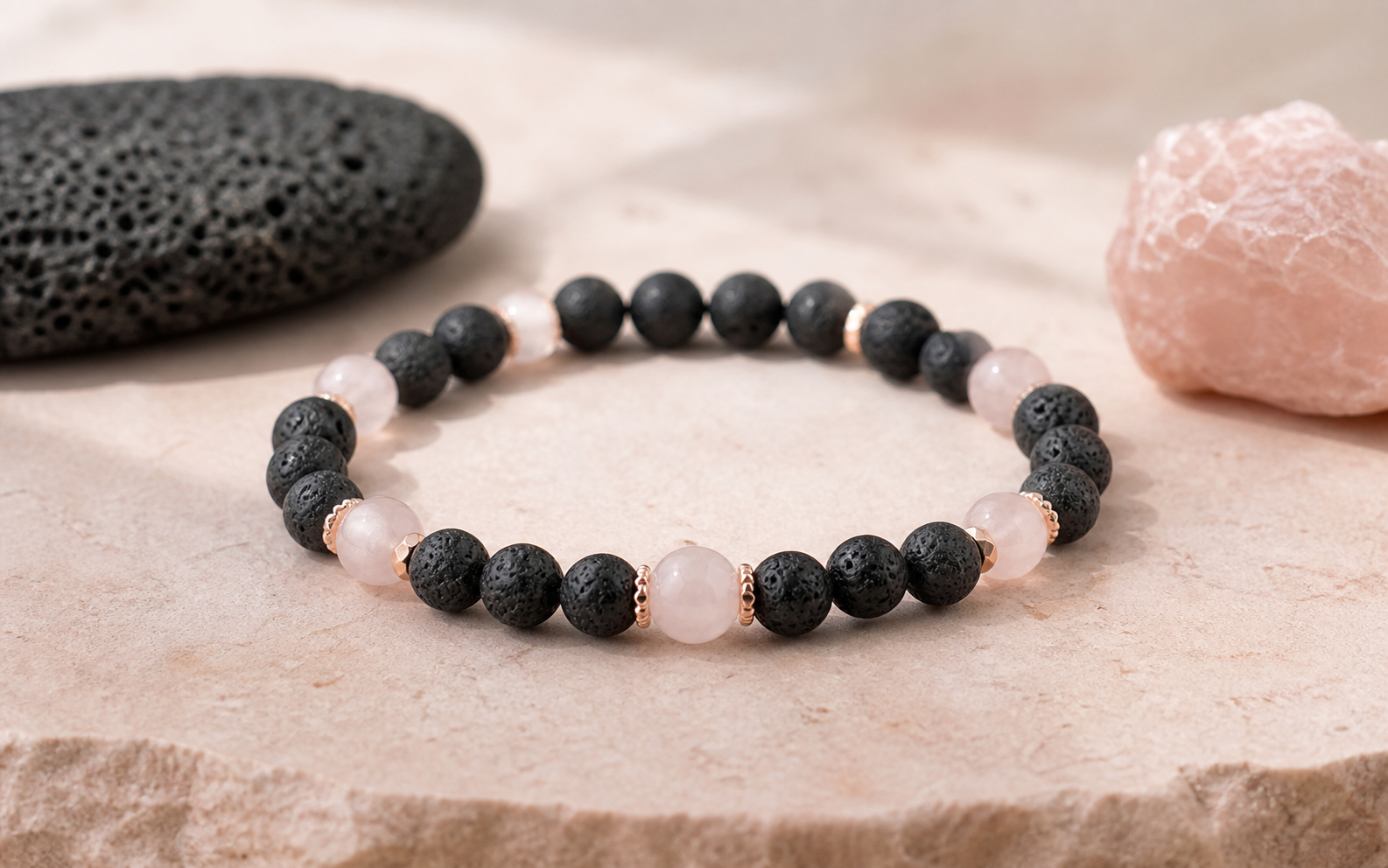 Bracelet en pierre de lave noire et quartz rose sur un décor rose poudré