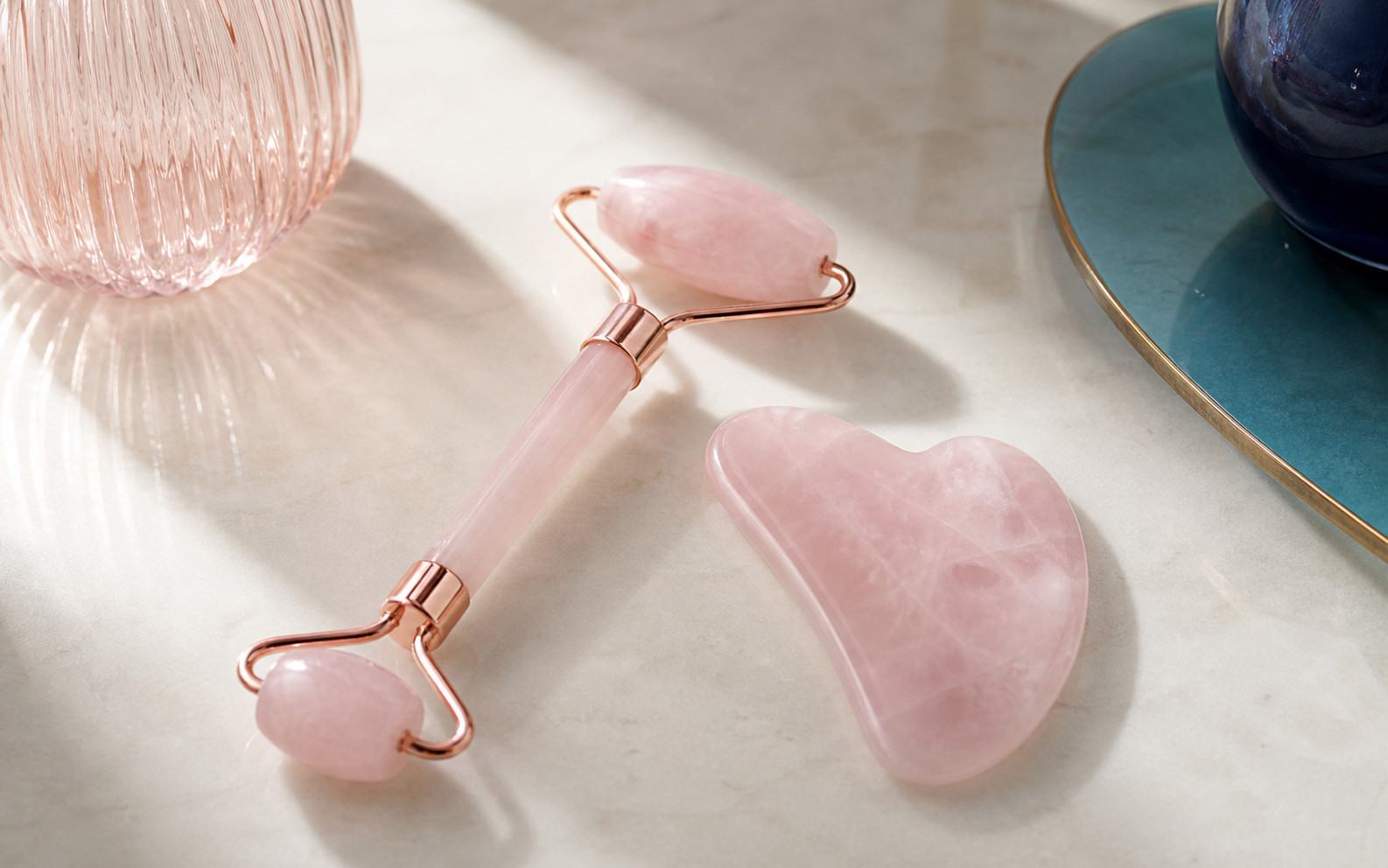 Roller visage et gua sha en quartz rose côte à côte